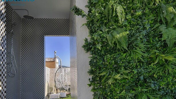 Quarto de hotel com piso xadrez, uma cadeira suspensa e vista para um edifício com cúpula.