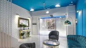 Uma sala de estar moderna com teto azul, mesa de centro de vidro, poltrona preta e sofá verde-água.