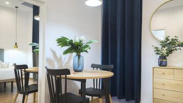 Habitación de hotel con comedor, espejo, cómoda y planta en maceta.