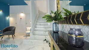 A modern hotel lobby with a marble staircase, a seating area, and a large mirror with decorative elements. - Hotelito Boutique Badalona Mar 3 (Badalona)