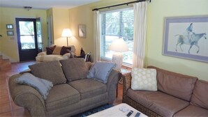 A living room with a sofa, a loveseat, a lamp, and a painting on the wall. - Ariel East Duplex 3 bedrooms, 2.5 bathrooms (Jekyll Island)