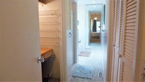 A narrow hallway leading to a bathroom with a shower, tiled walls, and a visible towel rack. - Ariel East Duplex 3 bedrooms, 2.5 bathrooms (Jekyll Island)