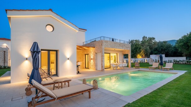Une maison moderne dotée d’une piscine, d’un espace salon extérieur et d’une terrasse bien éclairée.
