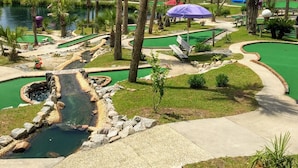 Ein Minigolfplatz mit Teich, Palmen und einer kleinen Brücke.