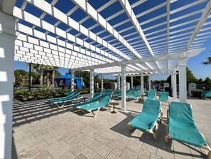 A covered outdoor lounge area with multiple sun loungers and a blue water slide in the background.