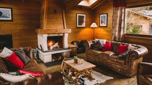 A cozy cabin interior with a fireplace, leather sofas, and wooden walls.
