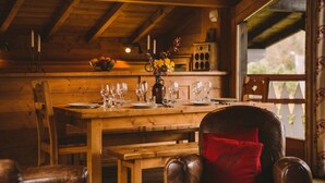 A wooden dining table set for four with wine glasses, a vase with flowers, and a candle holder.