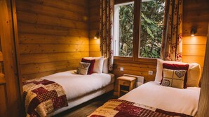 A cozy cabin room with two beds, each with a quilted bedspread and matching pillows.