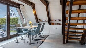 Un'area pranzo con un tavolo e sedie, una piccola pianta e una radio su uno scaffale.