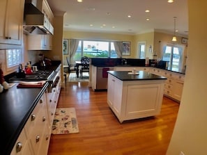 A spacious kitchen with a central island, wooden cabinets, and a dining area visible through the window.