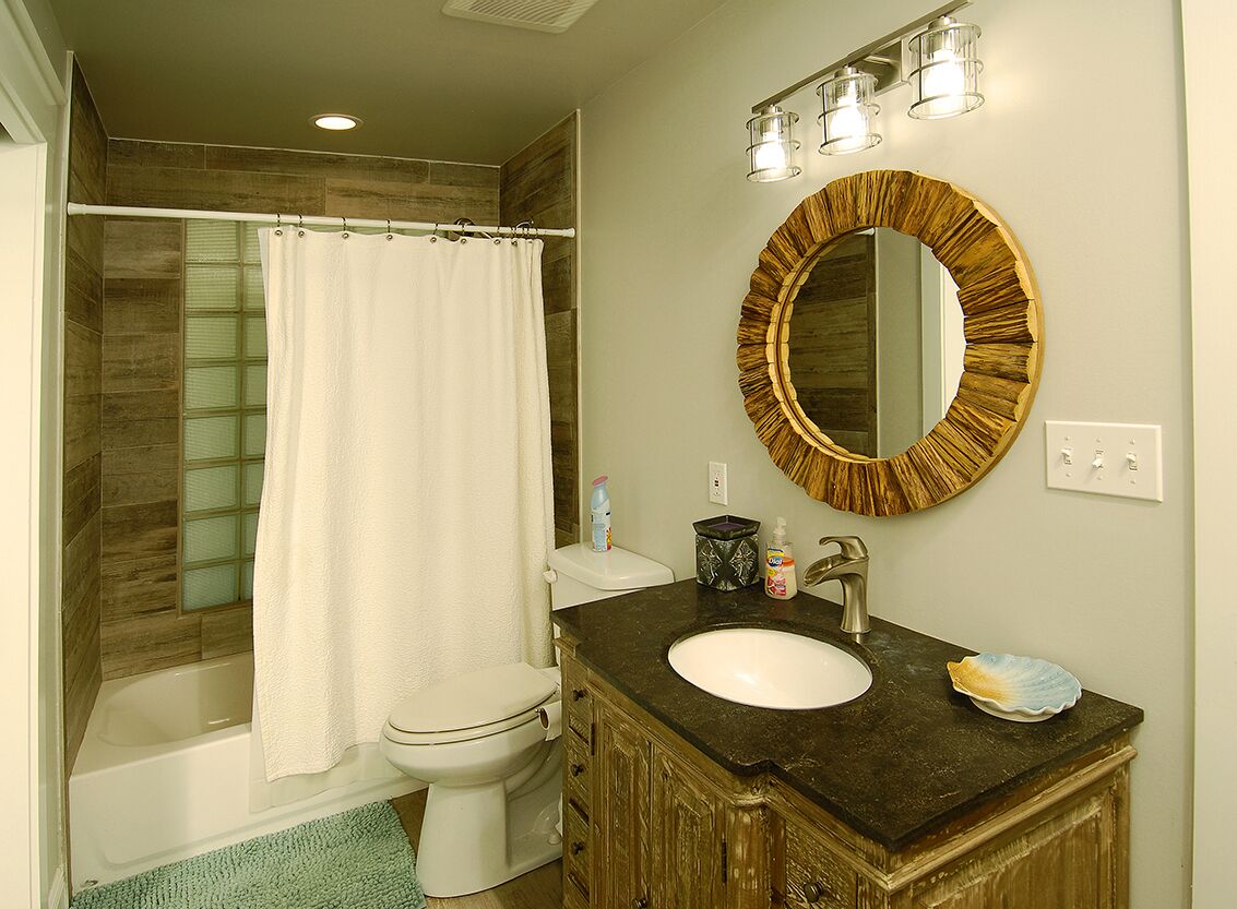 Une salle de bain comprenant une baignoire, des toilettes, un meuble-lavabo avec un évier et un grand miroir.