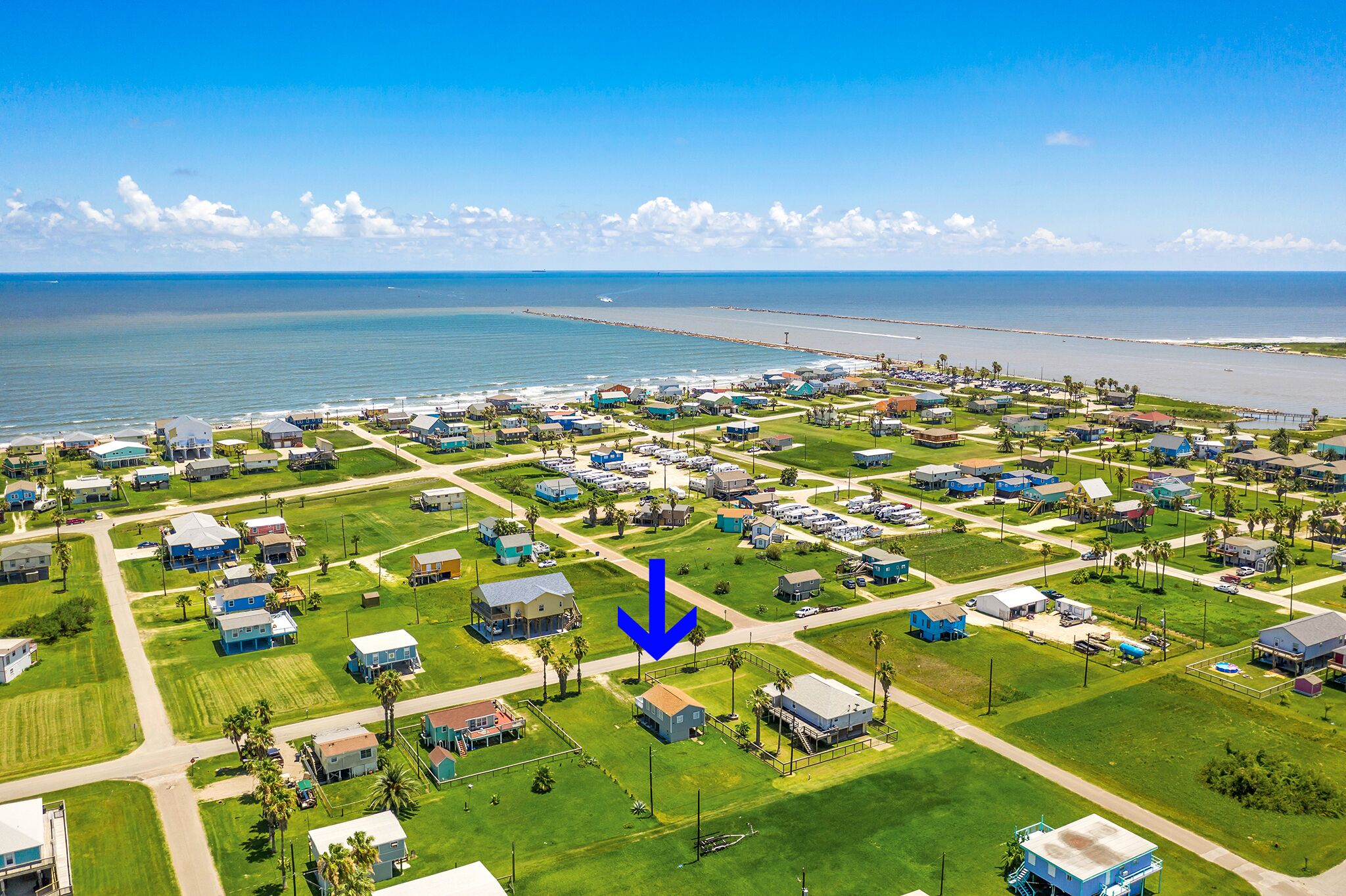 An aerial view of a coastal residential area with houses, roads, and a beach.