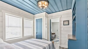 Een slaapkamer met een bed, een blauwe deur en een gang naar een andere kamer.