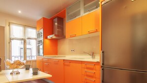 A modern kitchen with orange cabinets, stainless steel appliances, and a wooden floor. - Old Town Center: Origins and Tradition. (Bilbao)