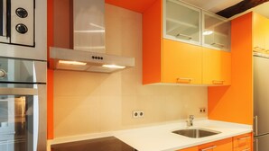 A modern kitchen with orange cabinets, stainless steel appliances, and a white countertop. - Old Town Center: Origins and Tradition. (Bilbao)