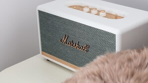 Un haut-parleur Marshall blanc, doté d’un panneau avant texturé et d’un objet duveteux au premier plan.