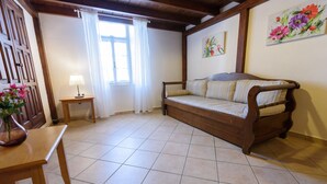Una habitación acogedora con un sofá de madera, una mesita, una lámpara y una ventana con cortinas.