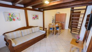 Una sala de estar acogedora con sofá, una mesa de comedor con sillas, un aparador de madera y una escalera.