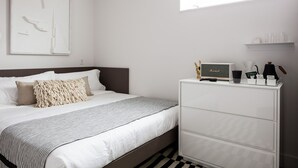 Un dormitorio ordenado con cama, cómoda y espacio para café.
