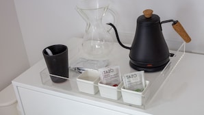 A coffee station with a coffee maker, a glass carafe, and a black mug on a white counter. - Boutique Hotel Suite above the Jefferson Theater on the Downtown Mall (Charlottesville)