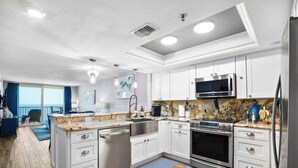 A modern kitchen with white cabinetry, stainless steel appliances, and a wooden floor. - Beachfront  Paradise (Indian Shores)