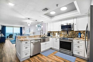 Une cuisine moderne avec des meubles blancs, des appareils électroménagers en acier inoxydable et un plancher en bois.