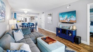 A modern living room with a sofa, ottoman, and a TV on a blue cabinet. - Beachfront  Paradise (Indian Shores)