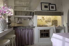A kitchen with white cabinets, a stove, and a hanging light fixture.