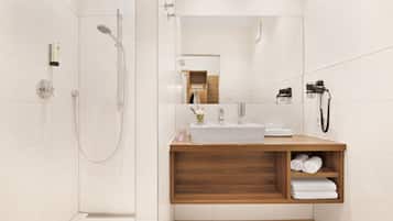 A modern bathroom with a shower, sink, and wooden vanity.