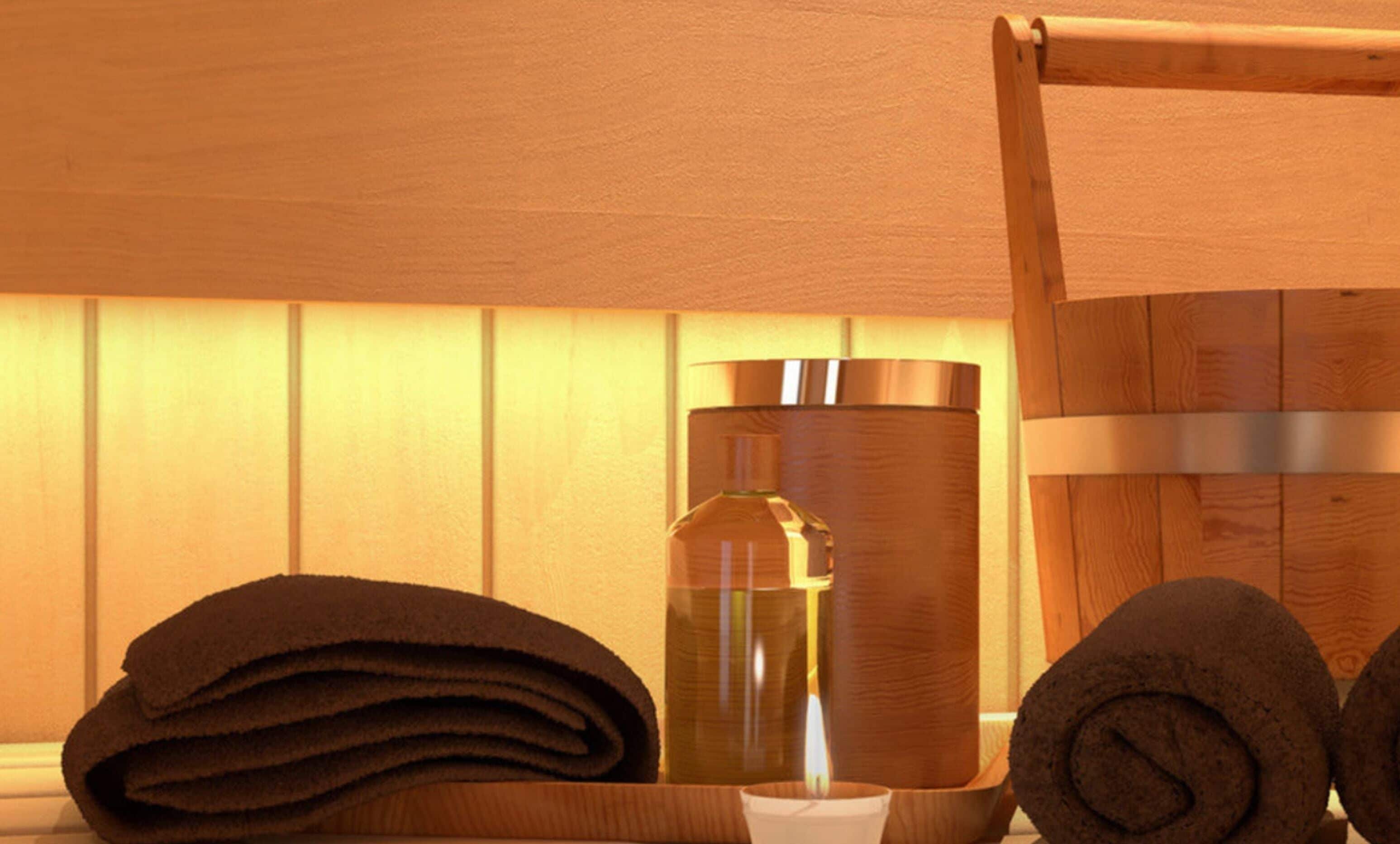A wooden bath tub with a towel and a bottle of lotion.