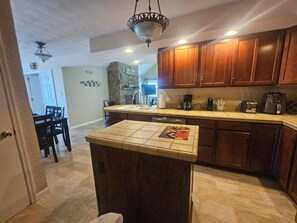 A kitchen with wooden cabinets, a stone accent wall, and a small island with a tile top.
