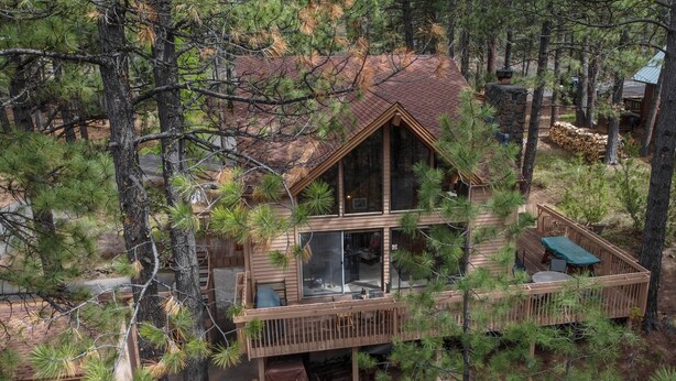 A cabin with a large deck, multiple windows, and a stone chimney. - Mink #8 Close to SHARC and 8 SHARC Passes! Close to Village! (Sunriver)