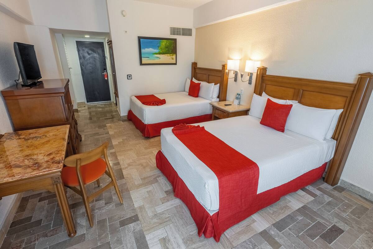 Une chambre d’hôtel avec deux lits, un bureau, une chaise et un téléviseur.