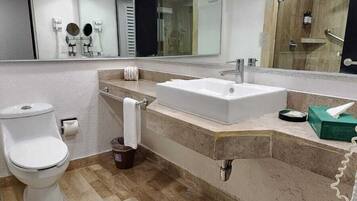 A modern bathroom with a white toilet, a sink with a mirror, and a shower area.
