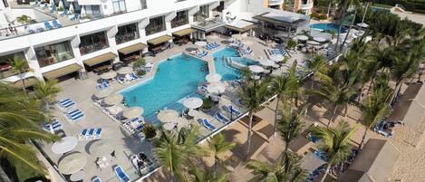 Una piscina al aire libre, sombrillas, sillones reclinables de piscina