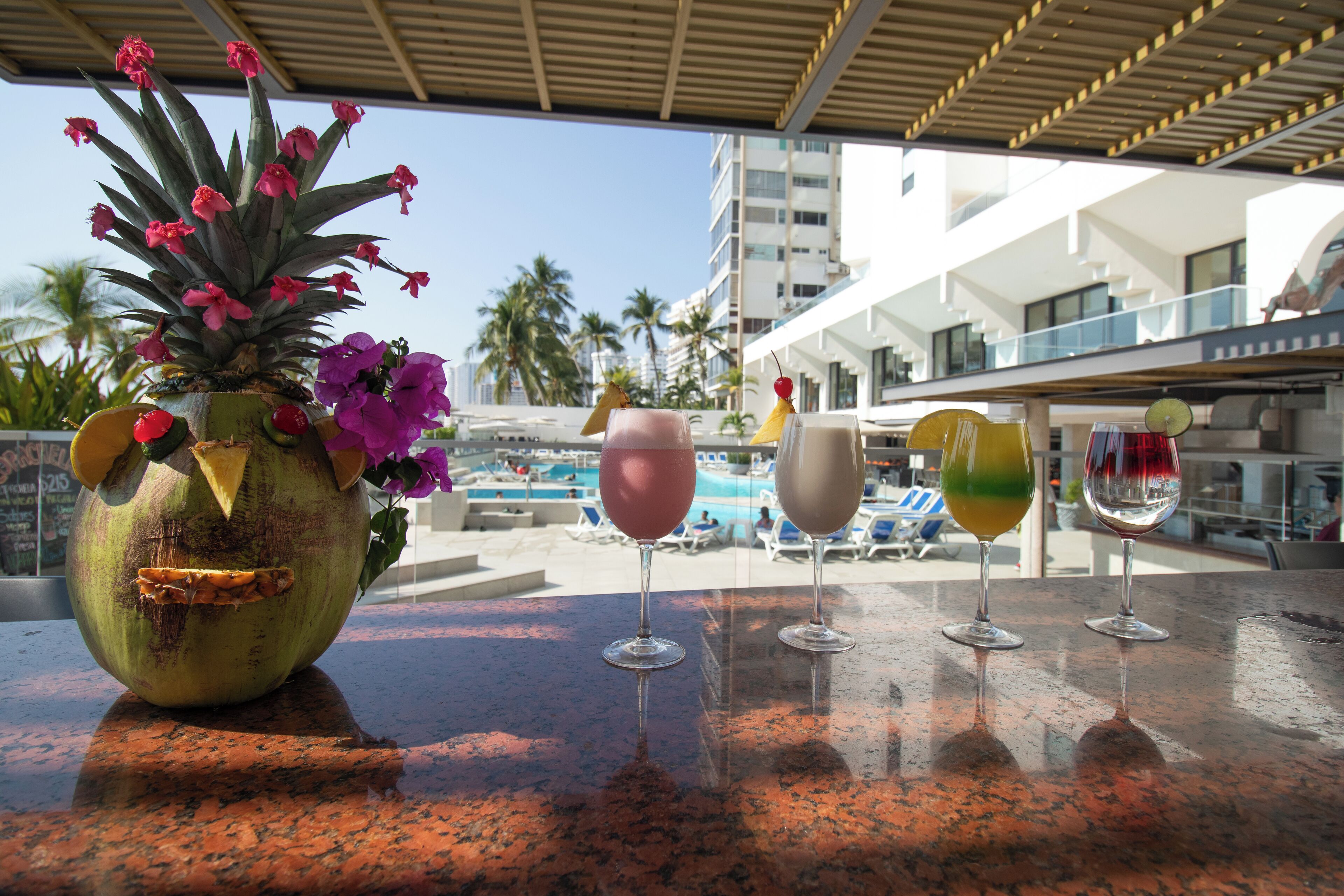 A tropical setting with a decorative pineapple centerpiece, a pool, and a modern building in the background.