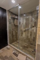 Ducha con cerramiento de vidrio, barandilla, paredes de azulejos y perchero.