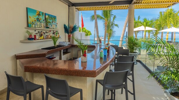 A bar area with a curved granite countertop, black bar stools, and a view of the ocean. There are potted plants and a painting on the wall. - Copacabana Beach Hotel Acapulco (Acapulco)