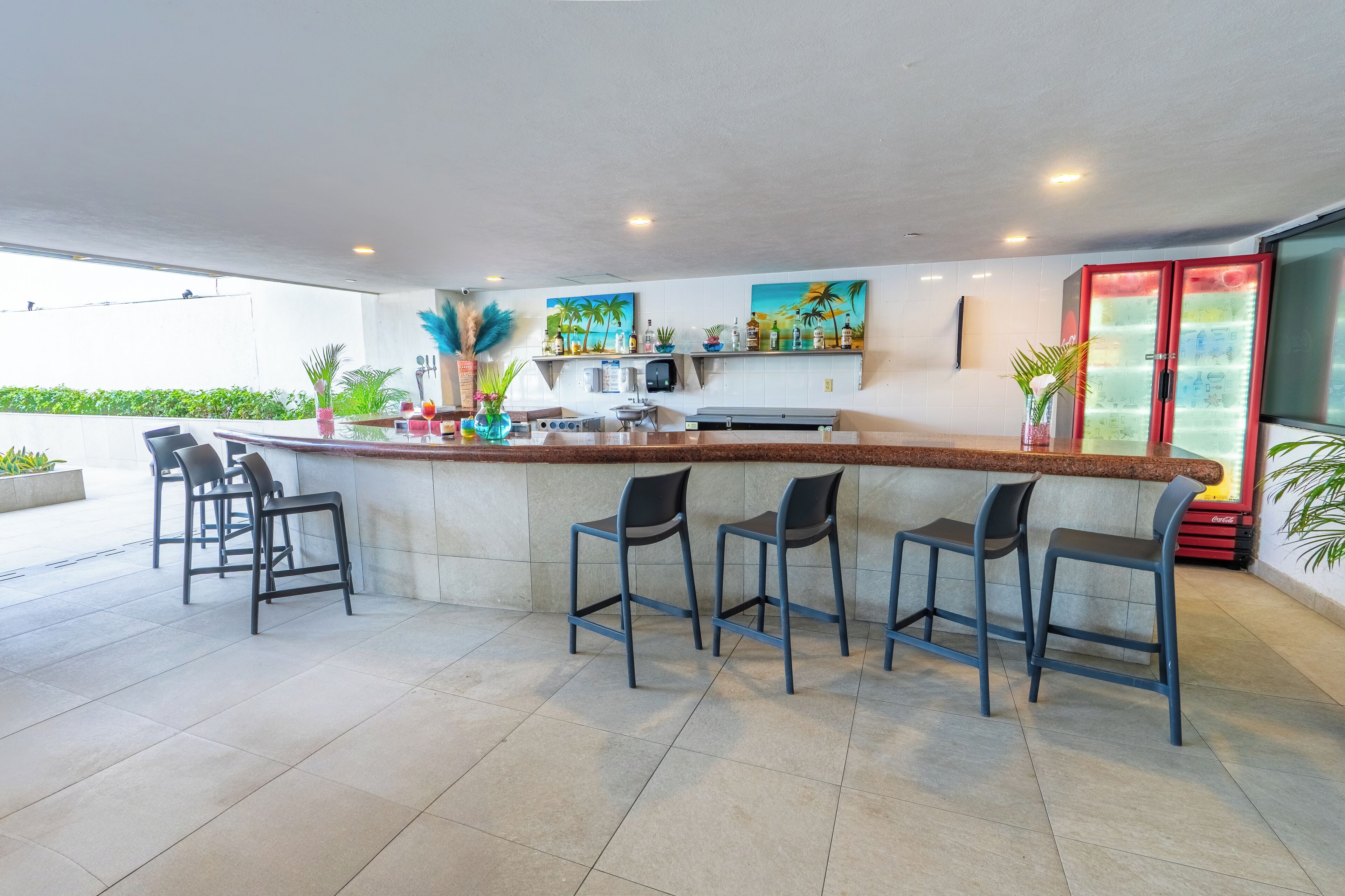 Un área de bar moderna con una barra larga, varios taburetes y un refrigerador.