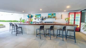 Un área de bar moderna con una barra larga, varios taburetes y un refrigerador.