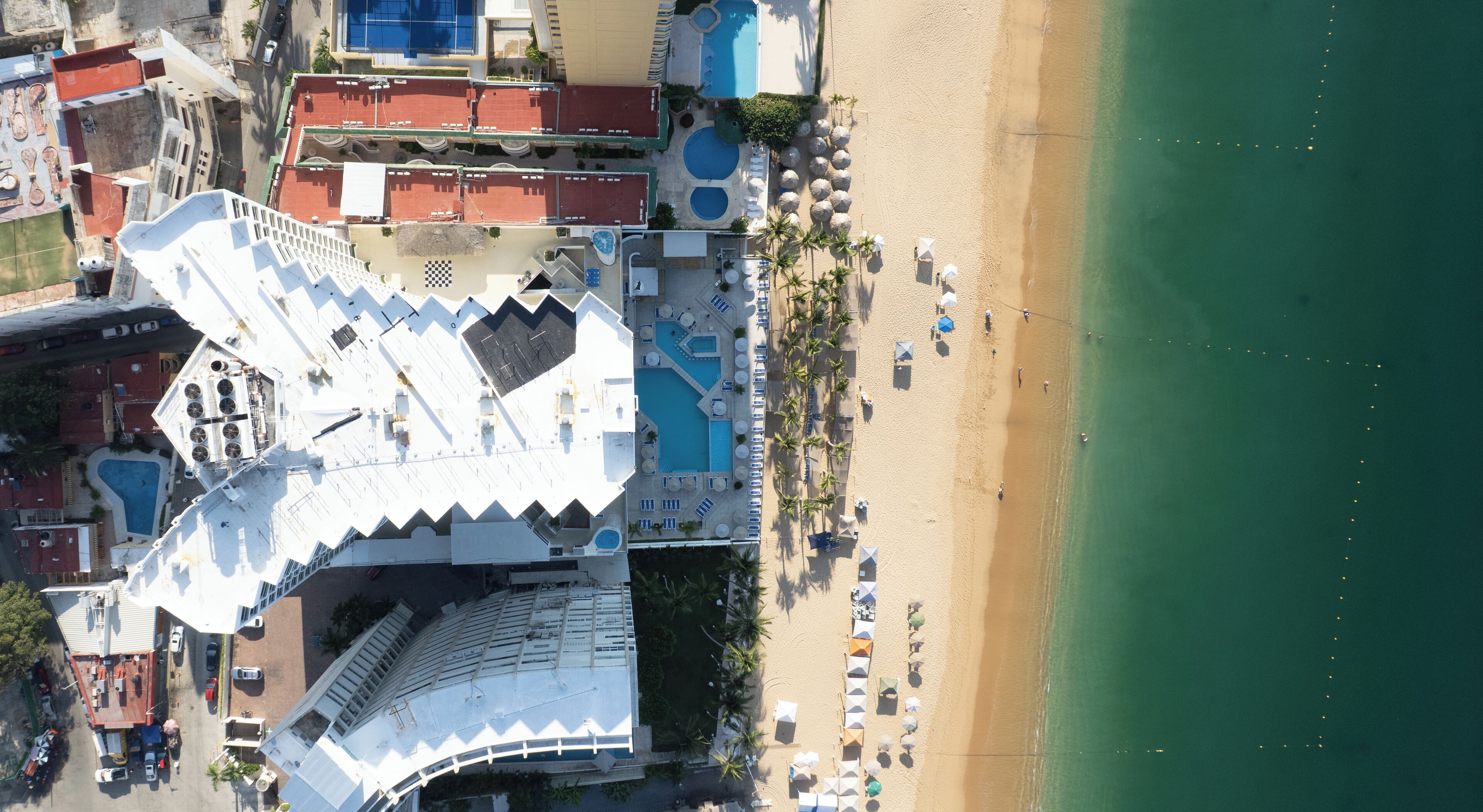 Vista aérea de un resort con piscina, playa y varios edificios.