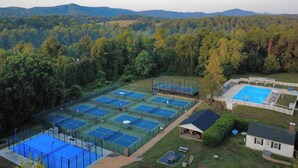 An aerial view of a tennis facility with multiple courts, surrounded by dense forest and hills. - Ramsay Estate Carriage House – Luxury Retreat with Mountain Views (Greenwood)