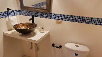Een badkamer met een wit wastafelmeubel, een spiegel erboven, een toilet en een blauw betegelde spatwand.