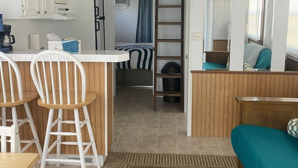Una cocina compacta equipada con microondas, cafetera y lavabo. Hay una zona de estar con sofá, sillas y una mesita.