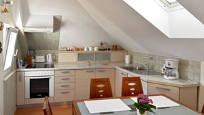 A modern kitchen with a dining area, featuring a built-in oven, a coffee maker, and a skylight. - Apartment FRANKA Split (Split)