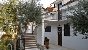 A two-story building with a staircase leading to a balcony, a potted plant, and a small doghouse. - Apartment FRANKA Split (Split)