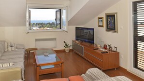 A modern living room with a sofa, a coffee table, a TV, and a view of the sea through a large window. - Apartment FRANKA Split (Split)