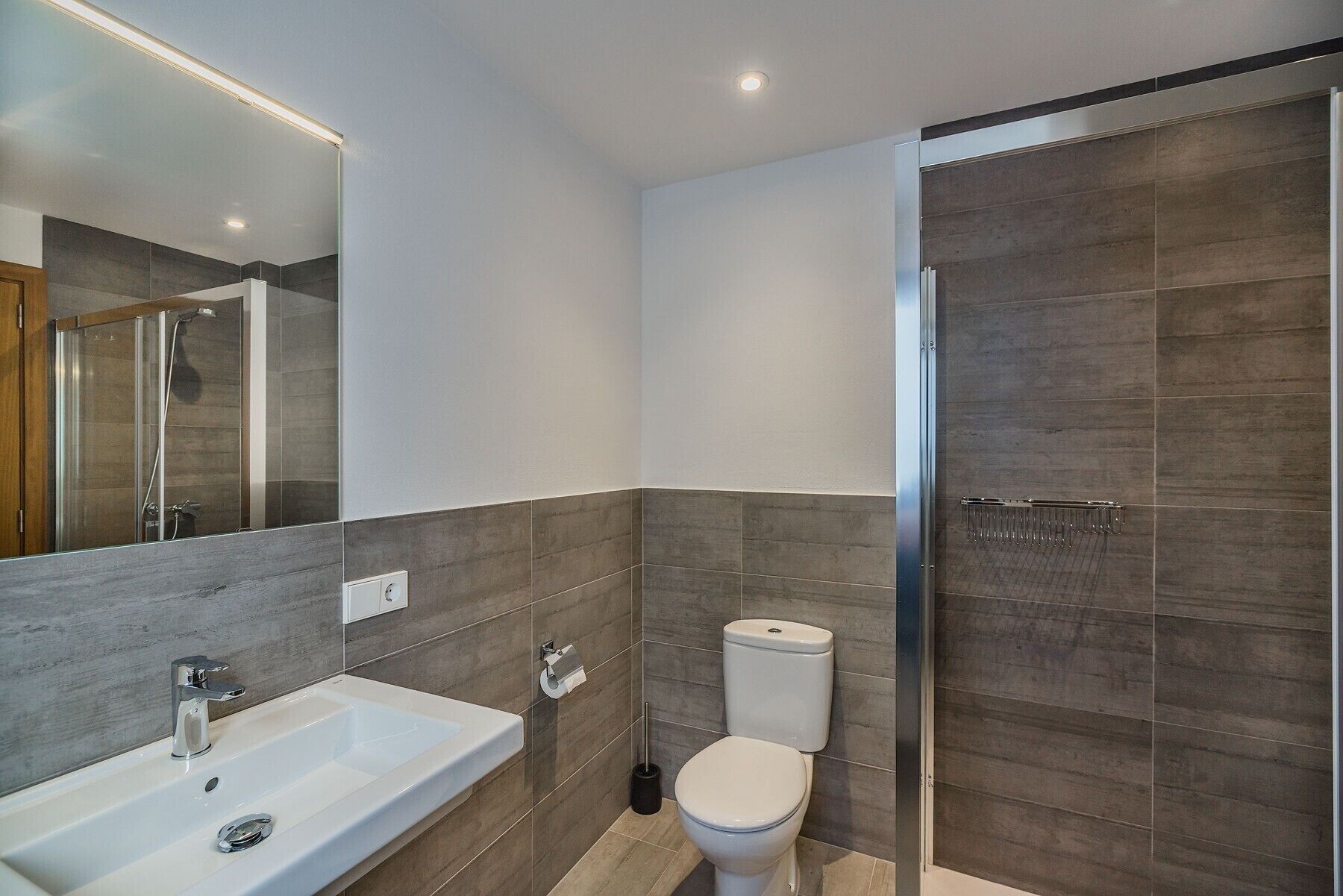 Une salle de bain moderne équipée d’une douche, de toilettes et d’un lavabo.