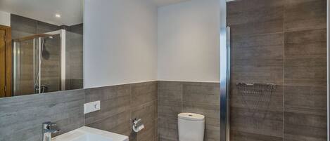 Une salle de bain moderne équipée d’une douche, de toilettes et d’un lavabo.