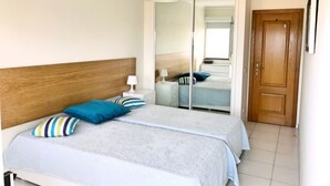 Een slaapkamer met een tweepersoonsbed, een houten hoofdbord, een spiegel, een kledingkast en een deur.